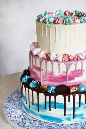 Three-tiered colored cake with colored smudges of chocolate on a light background. Picture for a...