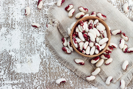 white-pink beans in a wooden cup on a light background