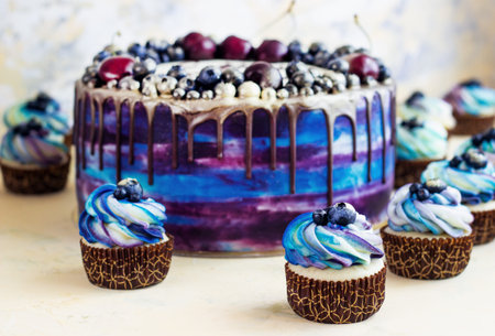 Bright festive blue cake with berries and chocolate and cupcakes with cream, candy bar, Sweet bar