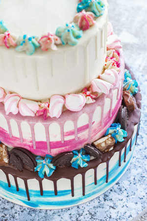 Three-tiered colored cake with colored smudges of chocolate on a light background. Picture for a...