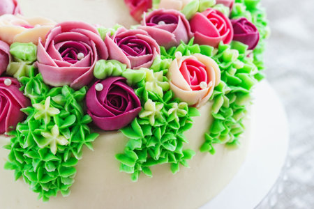 Bright festive white cake with bright flowers made of cream, a wedding cake, for a woman. Malaysian...