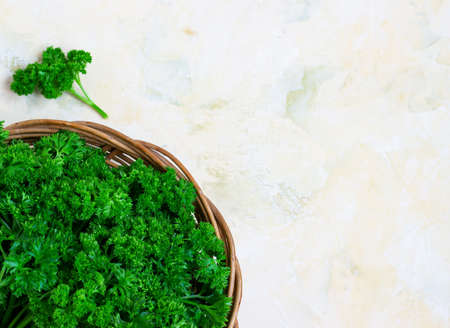 Fresh green parsley in a wicker wooden basket on a light backgroundの写真素材