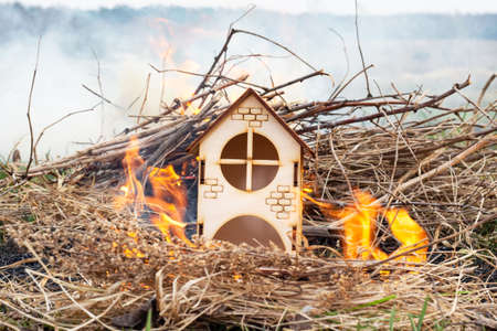 Wooden house or barn burning on fire. Dry grass is burning. Background. The toy house is on fire.の写真素材
