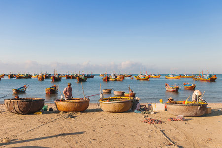 MUI NE, VIETNAM -  March 23, 2009. Fishing village, market and colorful traditional fishing boats near Mui Ne, Binh Thuan, Vietnam. Early morning, fishermen float to the coast with a catch.のeditorial素材
