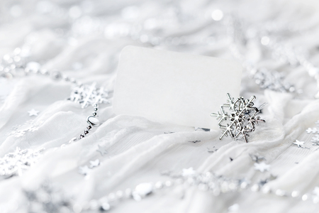 White holiday background with sparkling silver snowflakes, christmas decorations and empty piece of paper for your text.の写真素材