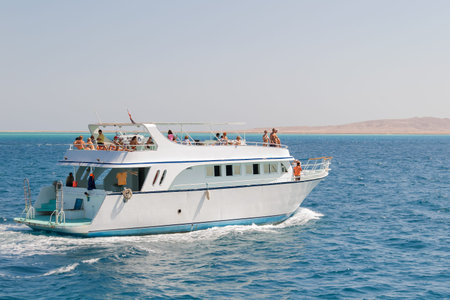 Tourists sailing on a yacht in the Red sea. Boat trip on bright sunny day. Hurgada, Egypt.