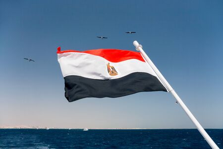 The national flag of Egypt is flapping in the wind above the Red sea.の写真素材
