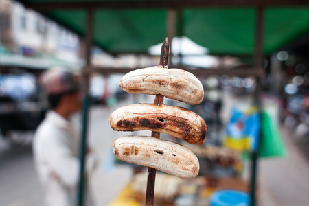 Traditional dessert in Asia - fried bananas on stick. Tasty fruit is on sale in little street shop. Bangkok, Thailand.の写真素材