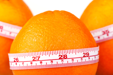 Three oranges with tailor's ruler. Orange diet. Fruit healhy vitamin diet helps to lose weight.の写真素材