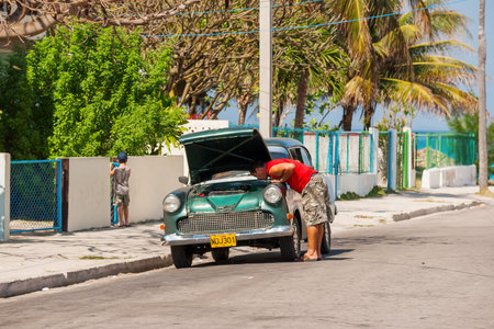 Man repairs his vintage car. Classic oldtimer car parked on street. Most of the Cubans drive cars that were on the road before 1959.のeditorial素材
