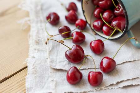 Fresh juicy sweet cherries  in old rusty mug. Rustic background with homespun napkin.