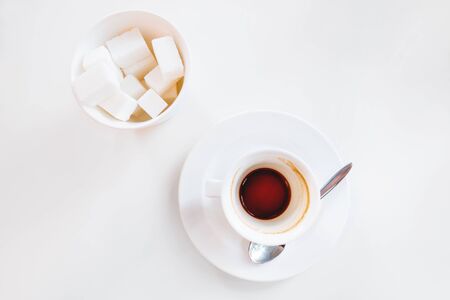Empty coffee cup and glass with sugar on white background. End of coffee break. Coffee grinds in white mug.の写真素材