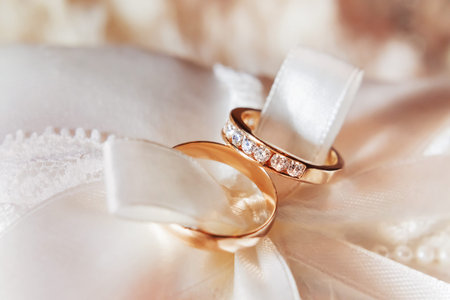 Golden wedding rings with diamonds on fabric. Wedding jewelry details. Engagement ring with precious...