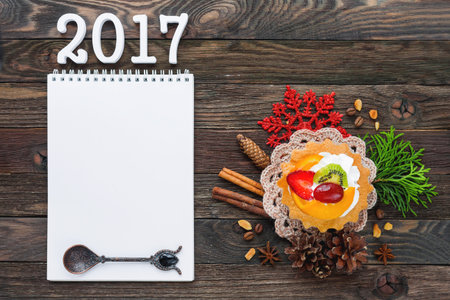 Christmas and New Year 2017 background with fruit tart, decorations and notepad. Mock up. Place for...