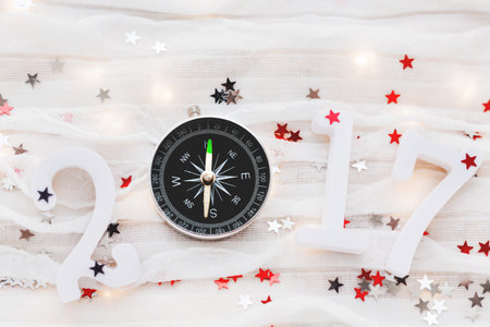 Christmas and New Year 2017 background. Travel symbol - compass, and confetti on white fabric.