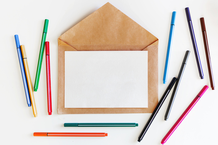 Clear sheet of paper on craft envelope. Background with colorful pens. Mock up. Flat lay, top view.の写真素材
