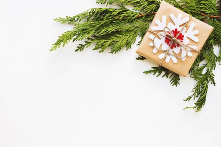 Christmas and New Year background with thuja branch and present wrapped in craft paper with snowflakes. Flat lay, top view. Place for text.の写真素材