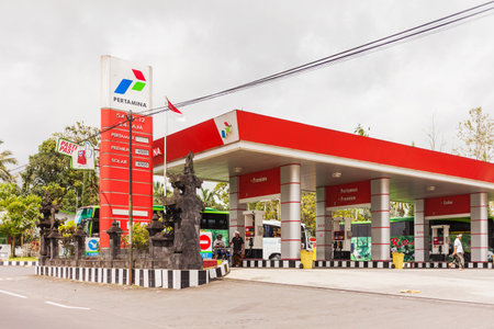UBUD, INDONESIA - January 26, 2013.  Petrol station employee fills bike with gas. Pertamina gas station.のeditorial素材