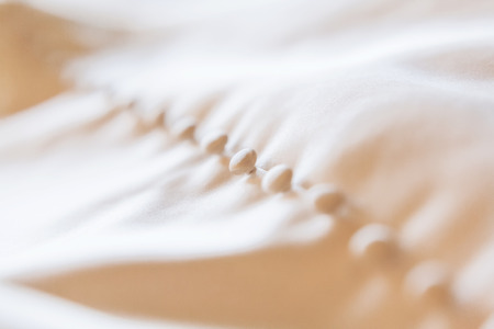 Lace silk fabric with buttons. Wedding dress detail. Selective focus.の写真素材