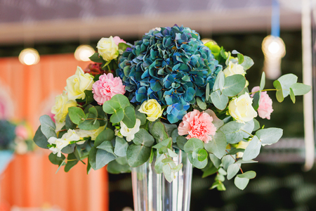 Table set for wedding banquet with floral composition of roses and hydrangea. Flower decoration in tall vase.の写真素材