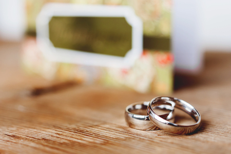 Pair of golden wedding rings on shabby wooden background. Symbol of love and marriage. Wedding invitation on background.の写真素材