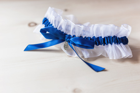 Bride's garter. Bride's traditional symbolic accessory. White laces with blue bow. Close up.の写真素材
