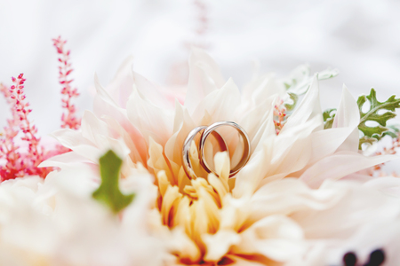 Pair of golden wedding rings lies inside flower in the bridal bouquet. Symbol of love and marriage. Traditional floral accessory for bride.の写真素材