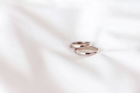 Golden wedding rings on white fabric background. Symbol of love and marriage.の写真素材