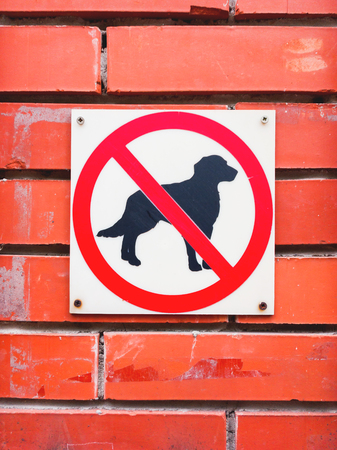 Sign on red brick wall - "Dogs are not allowed". Ban on walks with pet animals.の写真素材