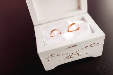 Pair of golden wedding rings with diamonds on white shabby decorative box. Beautiful symbol of love...