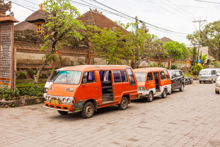 UBUD, INDONESIA - January 31, 2013. Old fashioned minivans on streets of Ubud. Old ornage cars parked on street.のeditorial素材