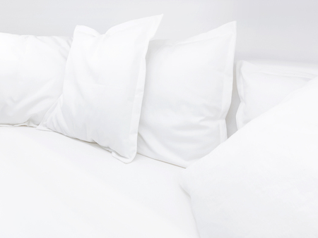 Few white pillows on bed. Clear white bed linen for restful sleep.の写真素材