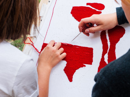Woman dressed in medieval clothes is teaching girl embroidery. Annual festival Times and Epochs. Historical reconstruction. Moscow, Russia.の写真素材