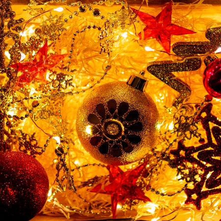 Cardboard box with Christmas and New Year decorations and light bulbs. Little baby touching red...