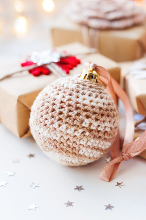 Christmas and New Year background with crocheted handmade ball, presents and decorations for Christmas tree. Holiday background with stars confetti and light bulbs. Place for text.の写真素材
