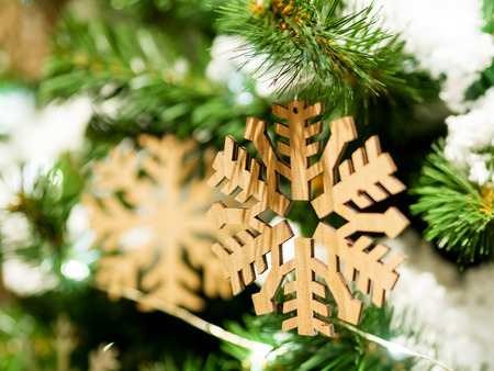 Christmas and New Year rustic decorations - wooden snowflakes on Christmas tree with light bulbs.の写真素材