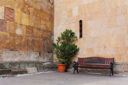 Bench and a tree in pot near the stone wall. Place for rest near Sioni Cathedral in Tbilisi, Georgia.の写真素材