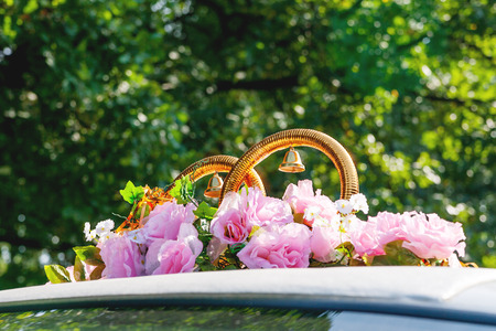 Artificial pink roses and golden rings with bells. Car decoration for wedding ceremony.の写真素材