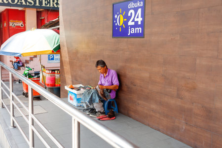 KUALA LUMPUR, MALAYSIA - February 01, 2013. Middle-aged man shining shoes on the street. Shoe...