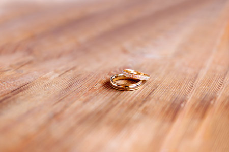 Pair of golden wedding rings with diamonds on shabby wooden background. Symbol of love, marriage and...