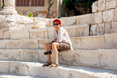ALEXANDRIA, EGYPT - Septemder 12, 2008. Tourist woman is sitting on ruins of the Roman amphitheatre of the IIâIV centuries.のeditorial素材