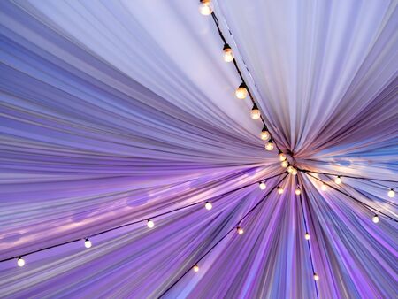 Vintage light bulbs with filament. Old fashioned lantern under ceiling of colorful fabric tent. Incandescent lamp, retro design.の写真素材