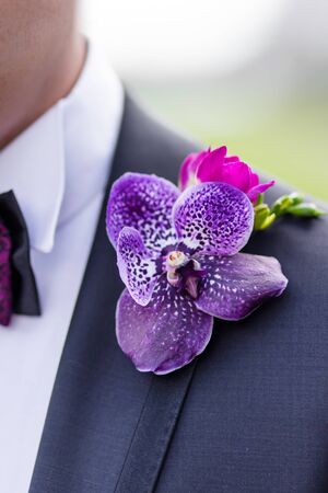 Boutonniere with freesia, violet orchid and pink rose with leaves. Traditional groom accessory at the wedding.の写真素材