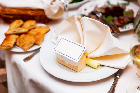 Table served for wedding banquet with guest cards. Salads, appetizers and glasses with wine.