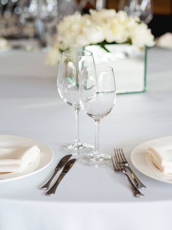 Table served for banquet with cutlery, wine glasses and napkins. Pastel colored decorations.の写真素材