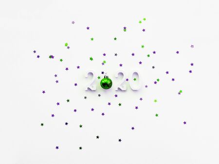 Christmas and New Year 2020 background with numbers, shiny green ball and violet star confetti. White copy space.の写真素材