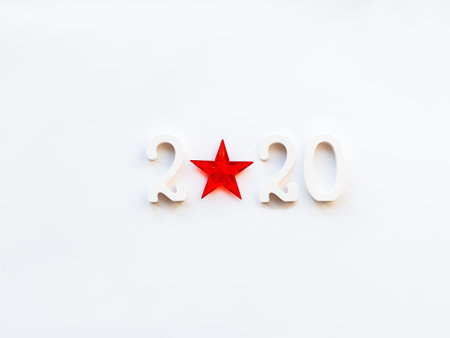 New Year 2020 background with bright red star. Numbers 2020 on white copy space with decorative ball...