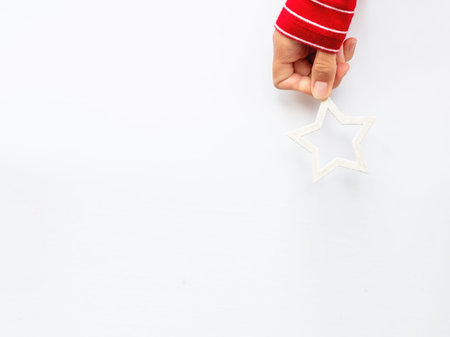 Woman in red sweater is holding New Year decoration - white star on white background. Top view on...