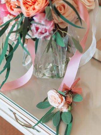 Bridal bouquet with pink and coral roses. Groom's boutonniere with similar flowers. Traditional accessories for wedding.の写真素材