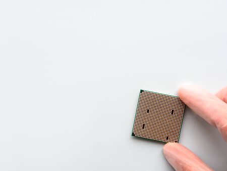 Hand in rubber glove with Central Computer Processor. CPU on light blue background. Technological detail of personal computer.の写真素材